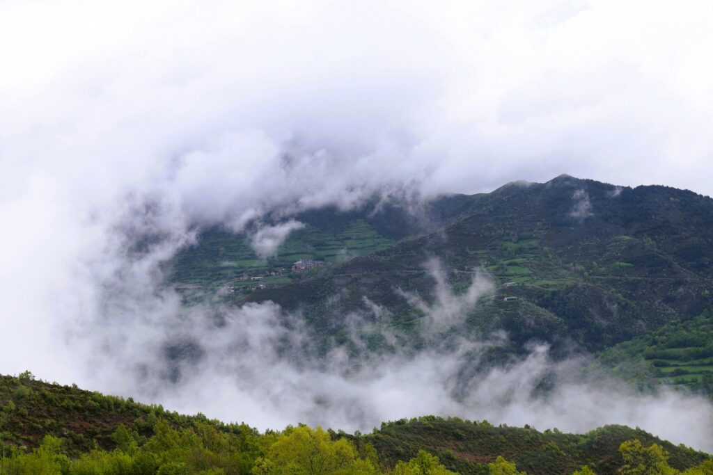 A serene and misty mountain landscape enveloped in clouds and lush greenery, perfect for nature and travel imagery.